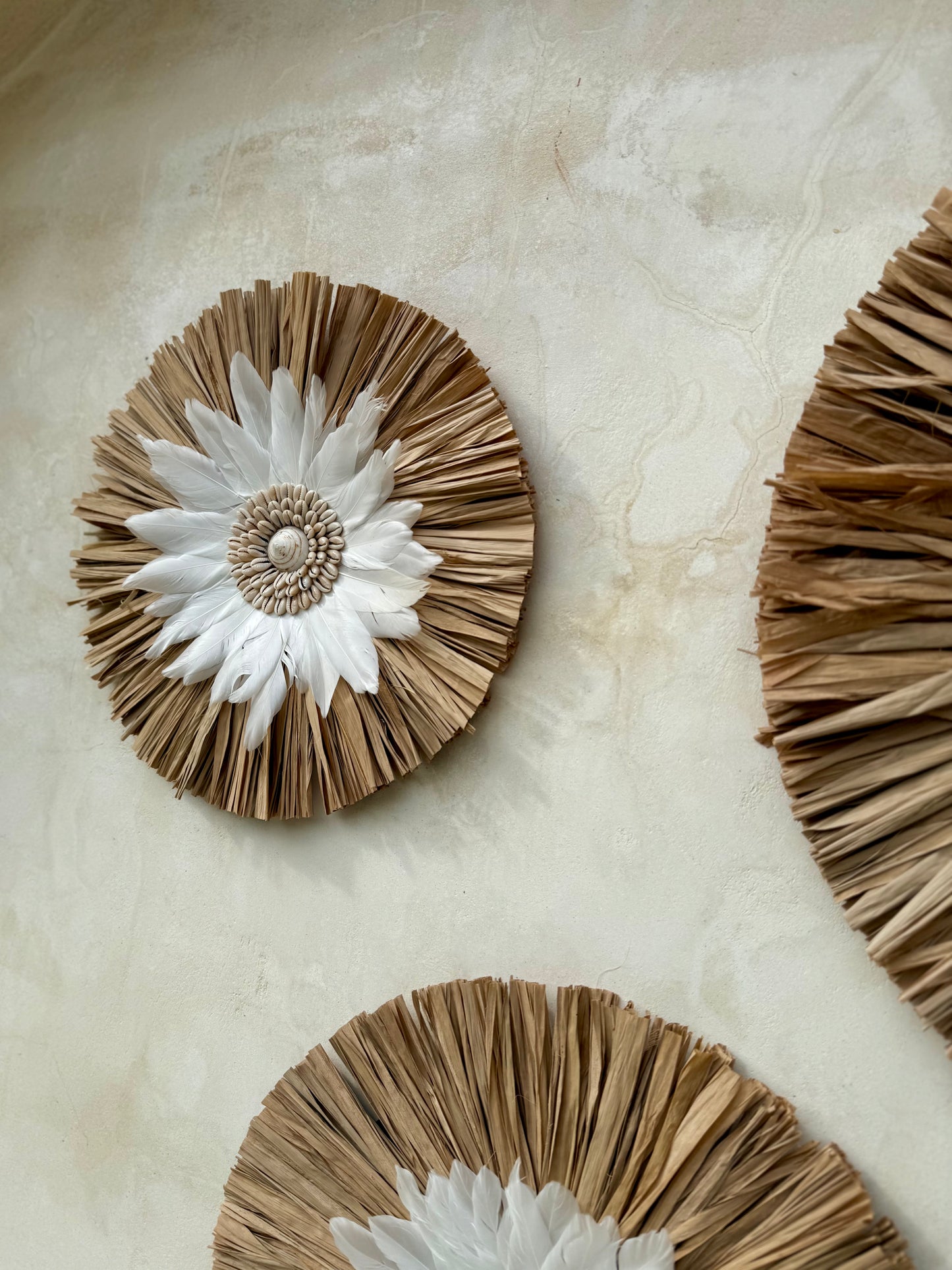 Décoration murale ronde bohème en coquillages et plumes blanches – création artisanale de Bali