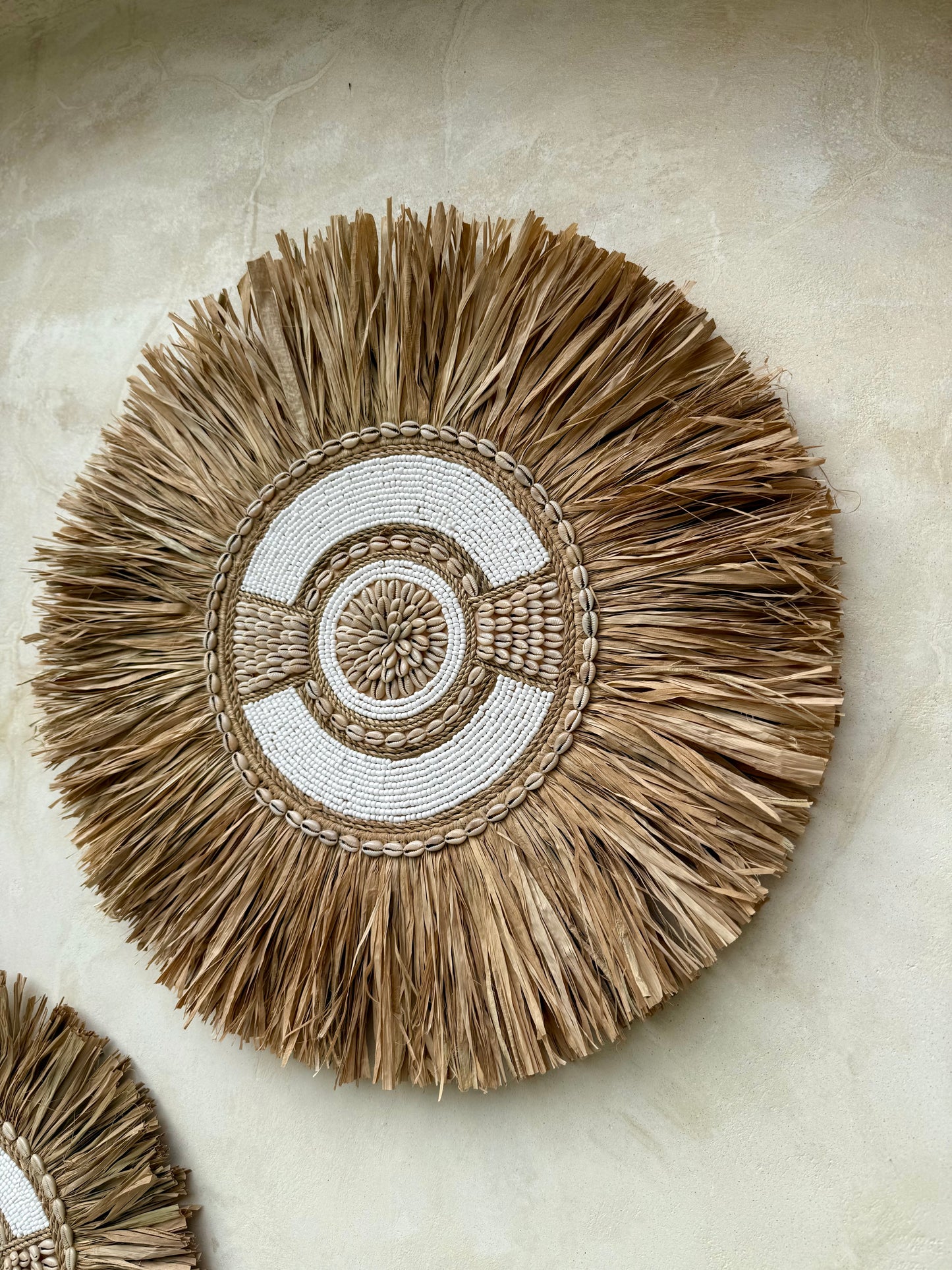 Décoration murale ronde en coquillages Cauri, perles blanches et cordelettes naturelles – création artisanale de Bali